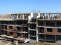 View of the apartment building. You can see the roof shape on the north part of the building and the brick work continuing on the lower levels of the building.